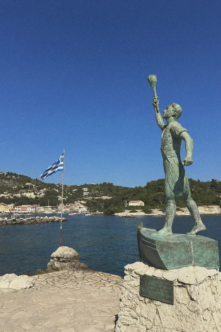 A bronze statue of a figure with a raised torch at the harbor of Gaios, symbolizing navigation and discovery