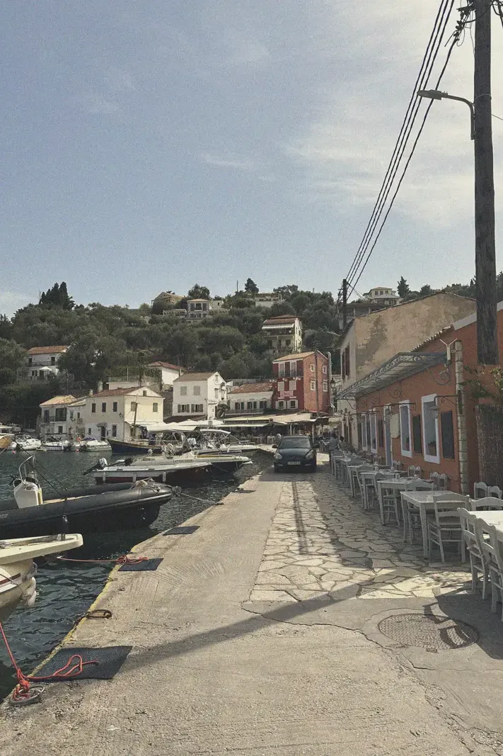 A peaceful harbor-side promenade in Loggos with moored boats and seaside dining