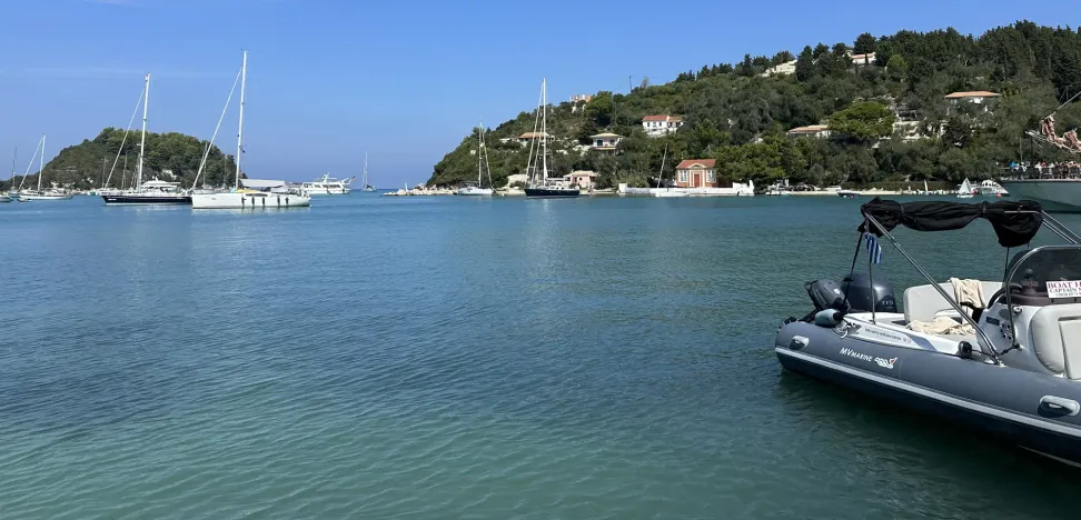Picturesque harbor view of Loggos village on Paxos Island, showcasing colorful houses and traditional Greek architecture amidst serene natural surroundings.